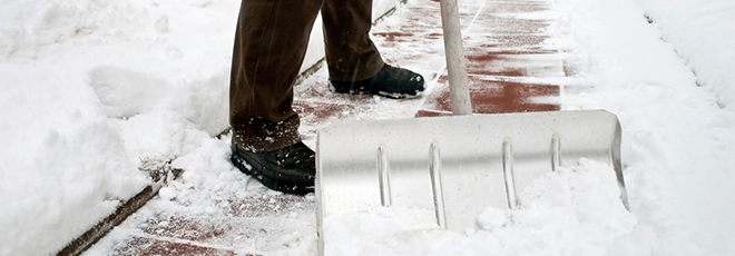 man shovelling snow from a sidewalk