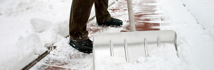 man shovelling snow from a sidewalk