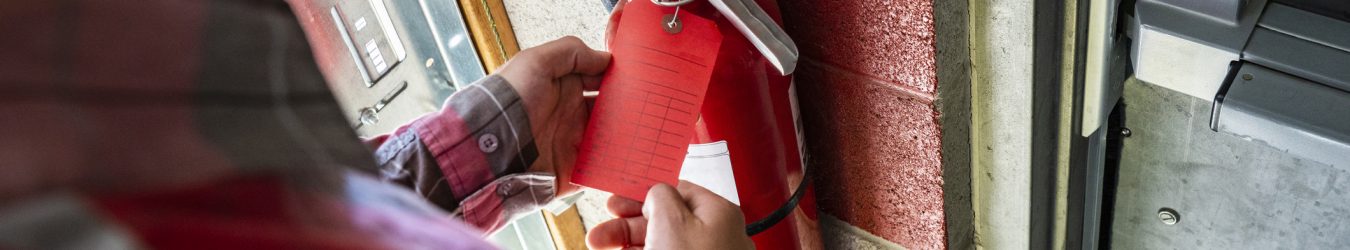 A person checks a fire extinguisher.