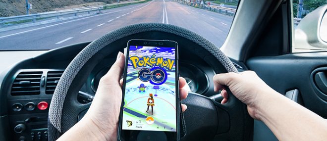 Person in car driving while playing Pokemon