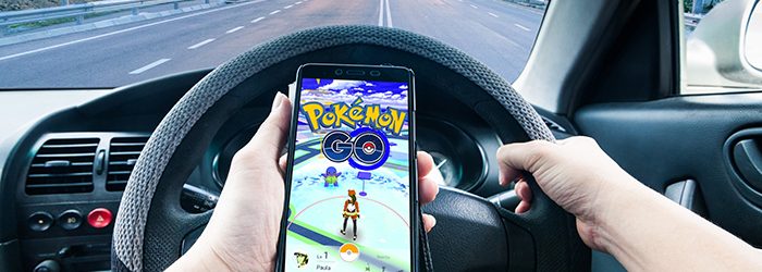 Person in car driving while playing Pokemon