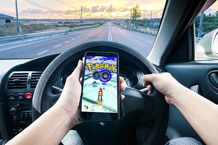 Person in car driving while playing Pokemon