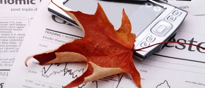 Red maple leaf on top of business documents on a table