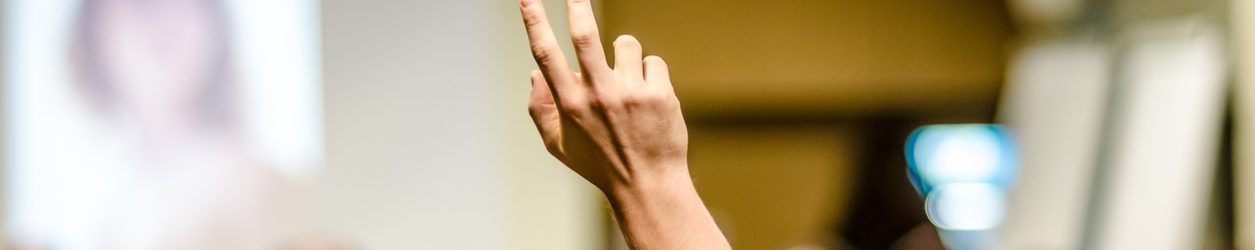 student with hand up in a classroom