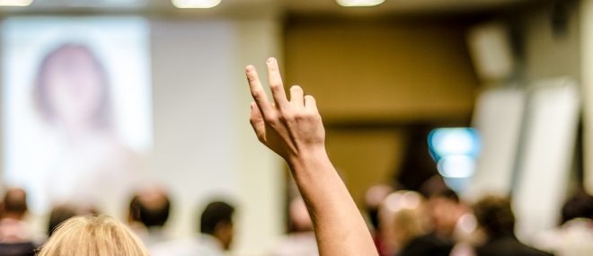 student with hand up in a classroom