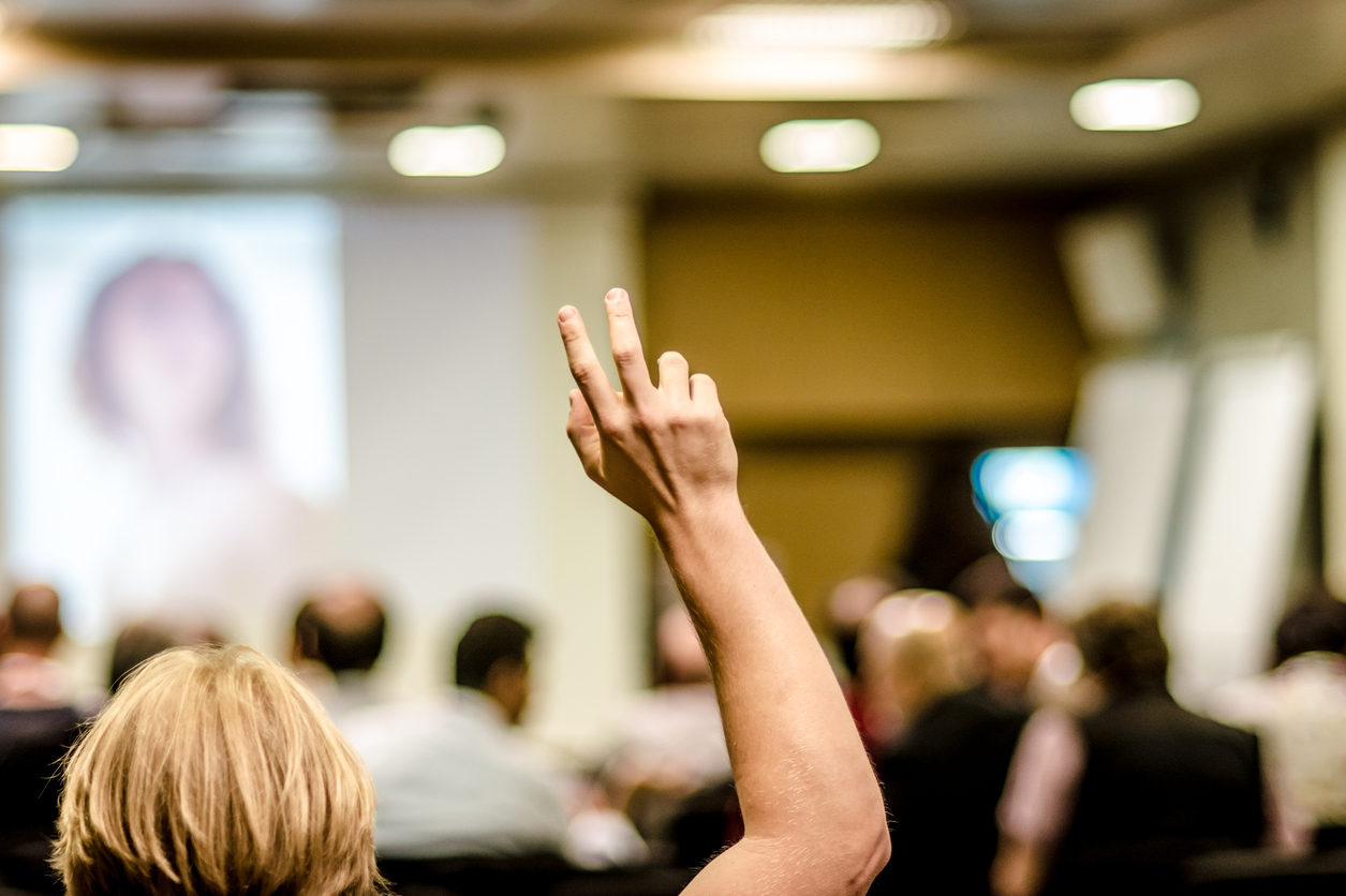 student with hand up in a classroom