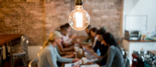 Brainstorming small business resources at a table under a light bulb.