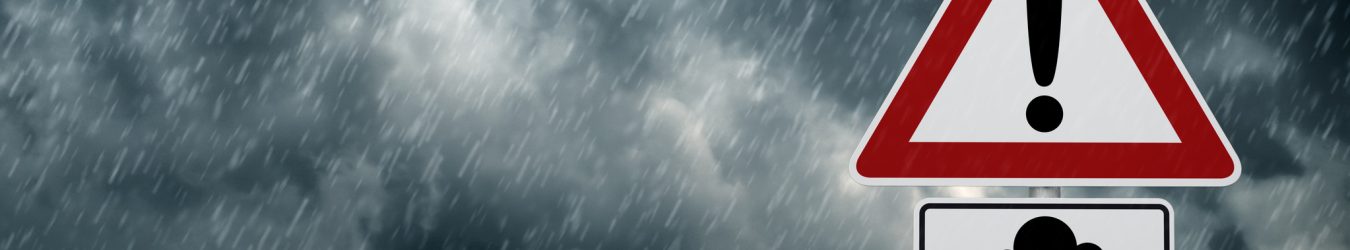 A dark cloudy sky with rain and warning sign