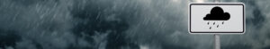 A dark cloudy sky with rain and warning sign