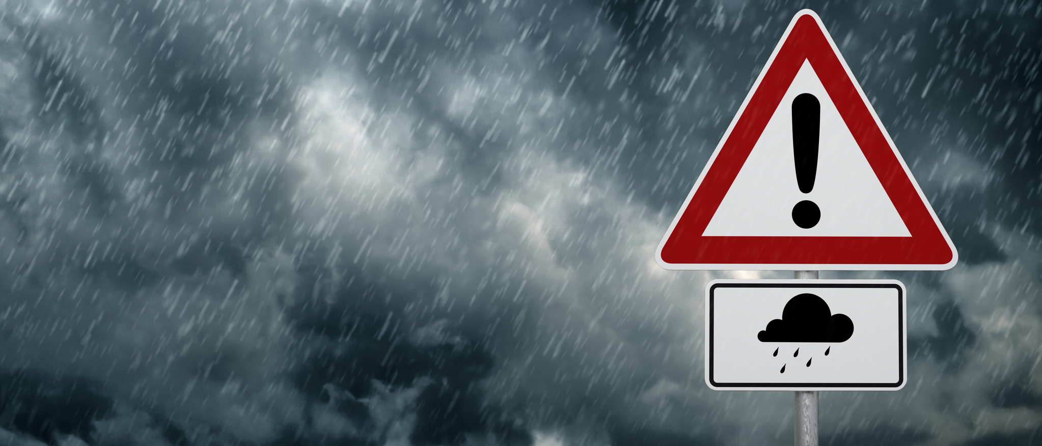 A dark cloudy sky with rain and warning sign