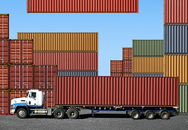 A freight container being loaded onto a truck at the docks.