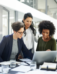 Three colleagues gathered around a laptop.