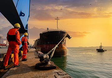 Two pier workers waiting for a boat to undock.