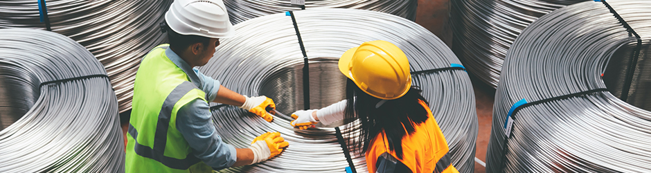 Two workers spooling metal wire in a manufacturing facility.