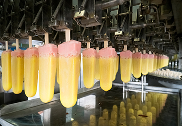 Freshly dipped ice cream popsicles on a conveyer belt.