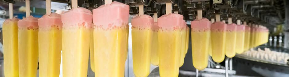 Freshly dipped ice cream popsicles on a conveyer belt.