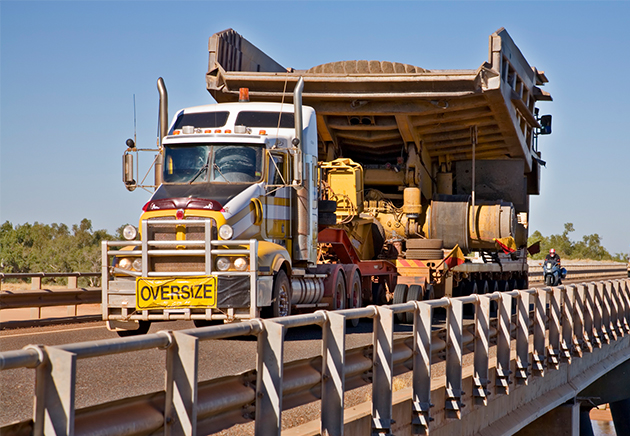 Oversized trailer crossing a bridge during the day.