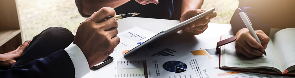 Business people in an office looking at a tablet while graphs charts are seen amongst them.