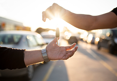 A person dropping car keys into another person’s hands.