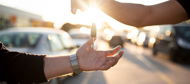 A person dropping car keys into another person’s hands.