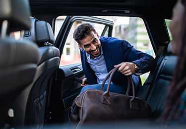 A man getting in to the back seat of a car.