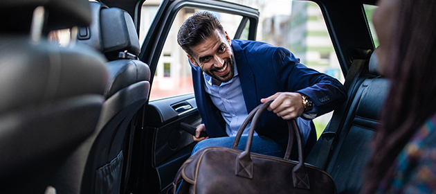 A man getting in to the back seat of a car.