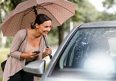 A woman outside the passenger side of a car confirming her ride.