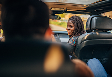 A woman in a car looking back at the passenger.