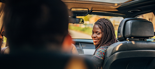 A woman in a car looking back at the passenger.