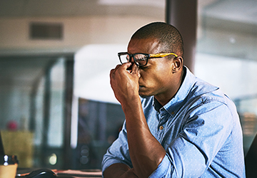 A man rubbing his eyes in a stressed position