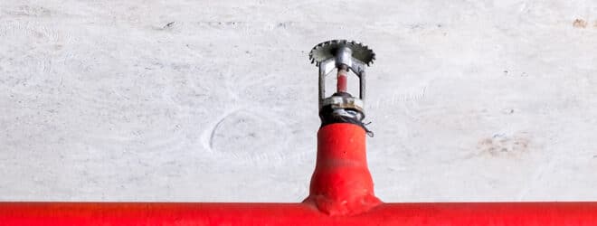 Automatic fire sprinkler on the red metal pipe.