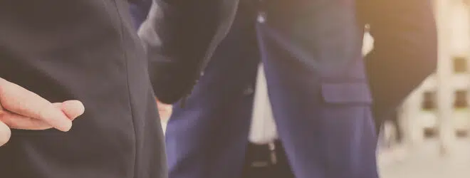 Businessman crossing his fingers behind his back.