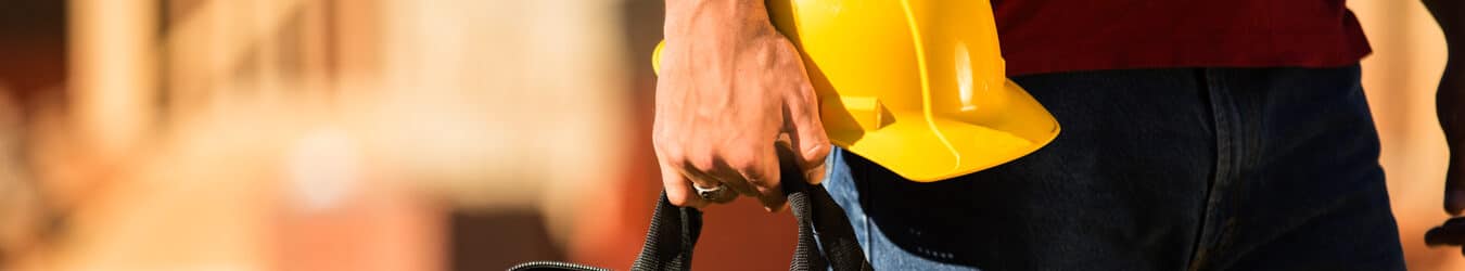 A construction worker holding tool box and a hard hat.