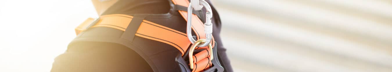 Industrial worker with safety protective equipment loop and harness hanging at his back.