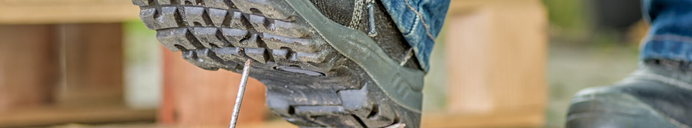 Worker with safety boots steps on a nail