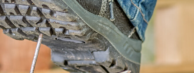 Worker with safety boots steps on a nail