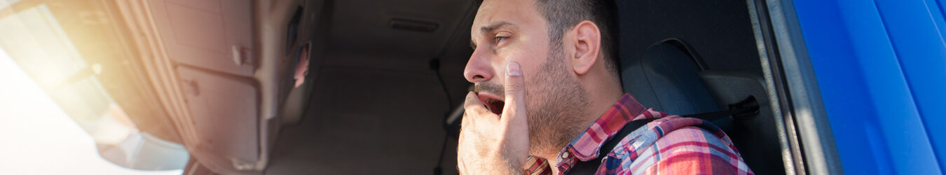 Truck driver yawning while driving.