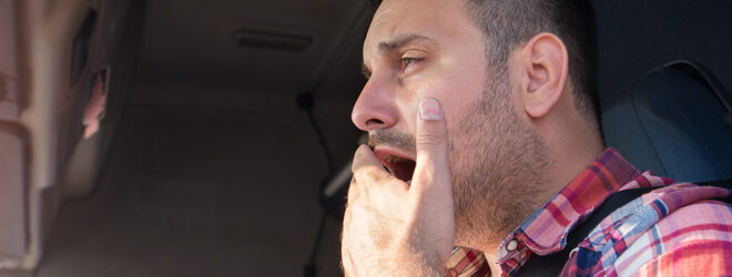 Truck driver yawning while driving.