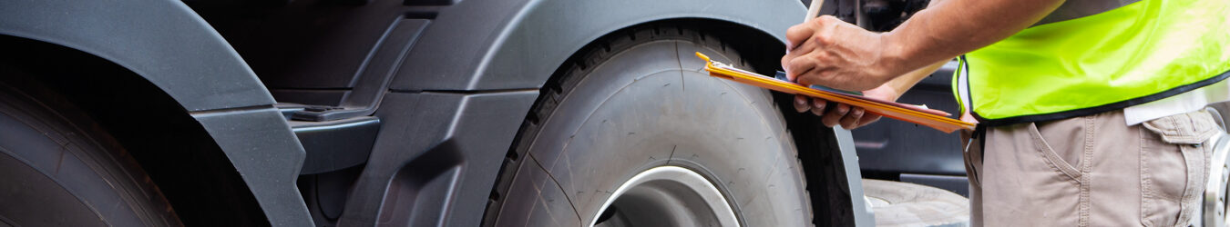 Truck driver inspecting check truck wheels.