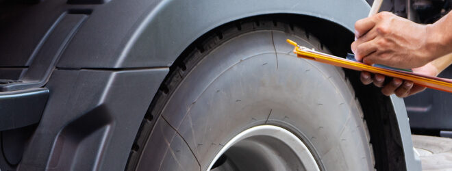 Truck driver inspecting check truck wheels.