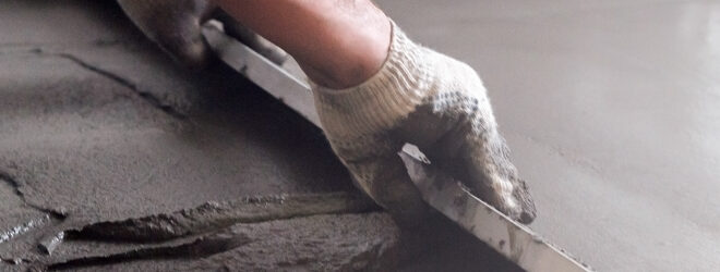 Worker levels a floor cement mortar