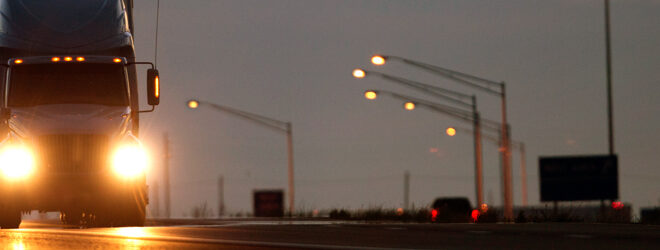 Two Semi diesel trucks on a highway at dusk.