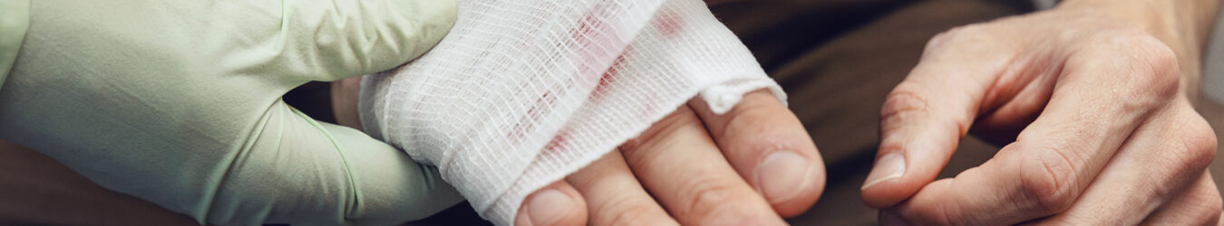 Doctor bandaging a businessman's hand.