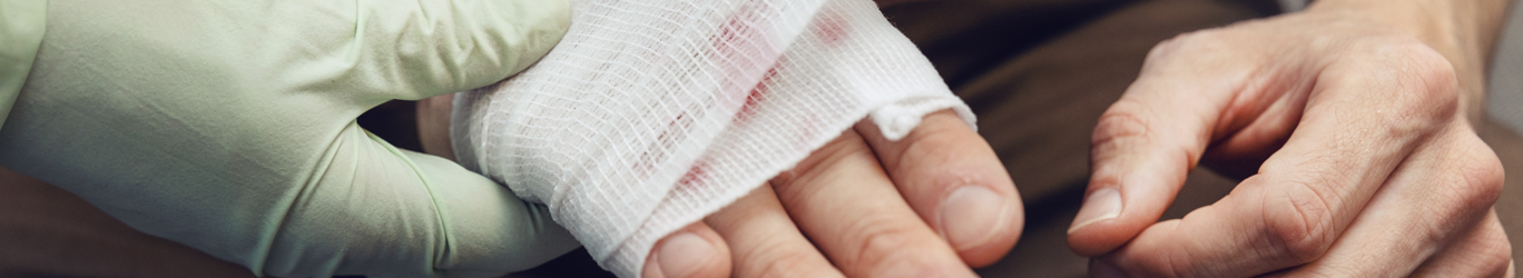 Doctor bandaging a businessman's hand.