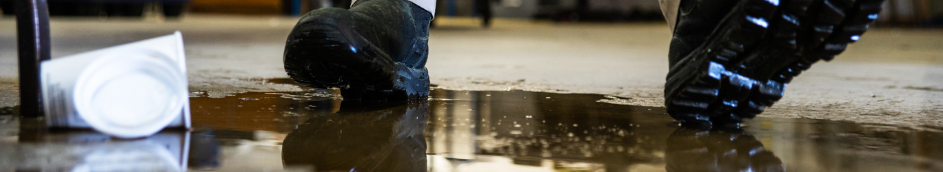 A worker in a warehouse walking in spilled liquid.