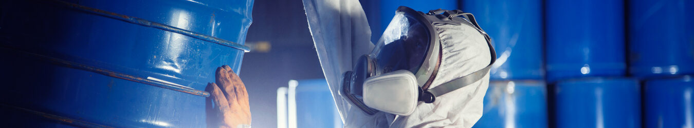 Worker rolling a barrel of chemicals.