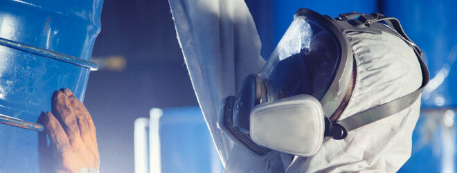 Worker rolling a barrel of chemicals.