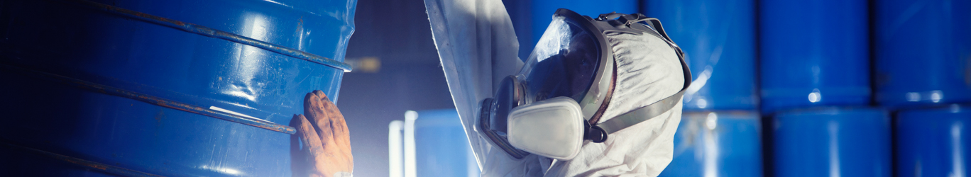 Worker rolling a barrel of chemicals.