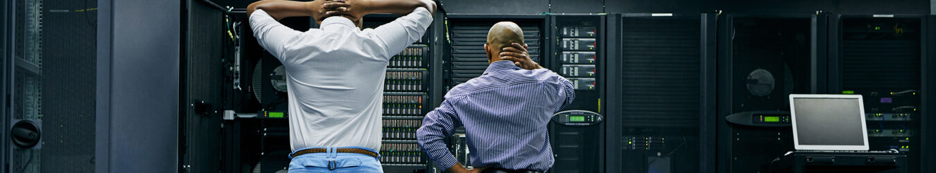 Two IT technicians repairing a computer in a data center.