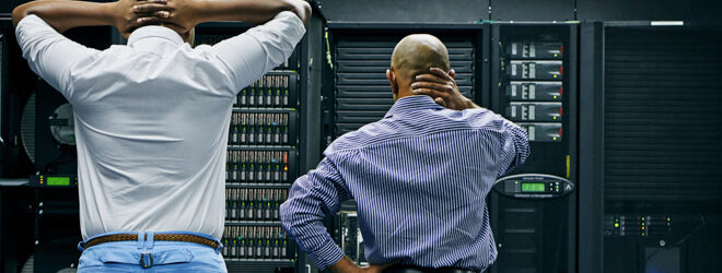 Two IT technicians repairing a computer in a data center.